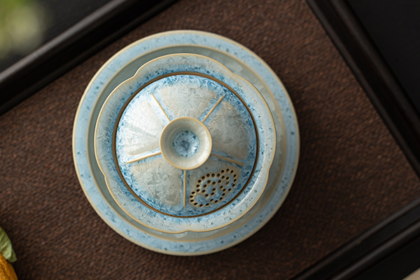 上から見た青い結晶釉の蓋碗と受け皿のセット。蓋には透かし彫りの穴があり、全体的に美しい模様が広がっている。