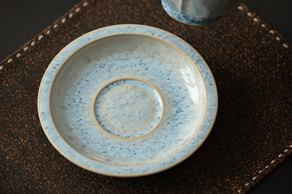 上から見た青い結晶釉の蓋碗と受け皿のセット。蓋には透かし彫りの穴があり、全体的に美しい模様が広がっている。