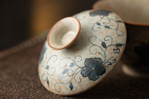 青花火石紅の唐草蓮文様が描かれた蓋碗の蓋のクローズアップ。中央に摘みがあり、細やかな花と蔓の模様が特徴。