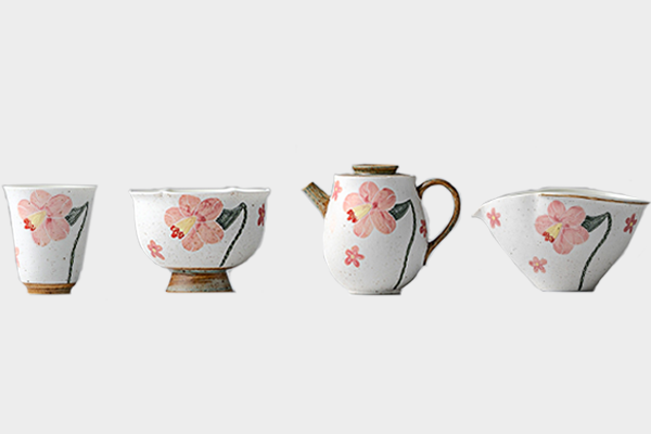 白い背景に並べられた、夕顔の花を彫り描いた陶磁器茶器セット。左から湯呑み、茶碗、急須、片口の順に配置されている。